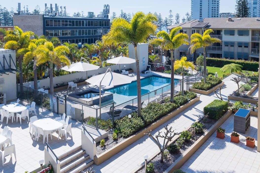 Burleigh Heads Accommodation Apartments with resort-style pool and palm-lined courtyard.